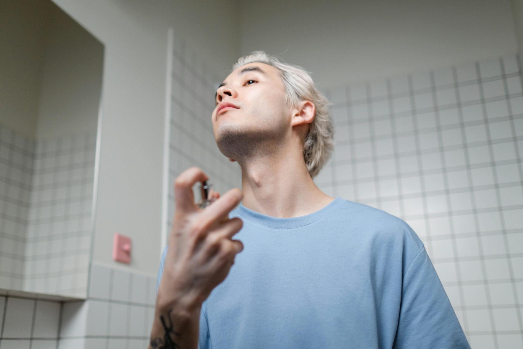 mężczyzna aplikujący na swoje ciało perfumy